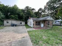 Exterior view of home with stone facade, porch, and detached garage with concrete driveway at 1521 Lewis St, Rocky Mount, NC 27804