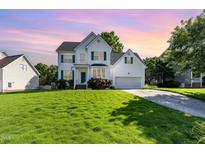 Charming two-story home with manicured lawn, attached garage, and inviting curb appeal under a lovely sunset at 1613 Patterson Grove Rd, Apex, NC 27502