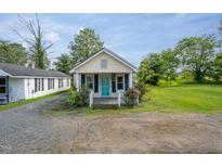 Charming cottage home featuring a quaint front porch and colorful landscaping at 306 W Main St, Pine Level, NC 27568