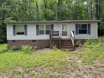 Single story home with brick foundation, light siding, blue shutters, and a small porch nestled in a wooded area at 3539 Charlies Ct, Wake Forest, NC 27587