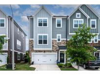 Charming townhome featuring a two-car garage and stone accents on the facade at 8415 Zinc Autumn Path, Raleigh, NC 27615