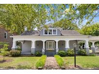 Charming gray home featuring a covered front porch, manicured landscaping, and a walkway leading to the inviting entrance at 125 W Pine St, Pine Level, NC 27568
