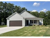 Charming single-story home featuring a front-facing garage and manicured lawn under a bright, cloud-dotted sky at 175 Oakfield Trace Dr, Four Oaks, NC 27524