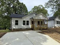 Charming single-story home featuring a welcoming front porch and newly paved driveway, complemented by lush green trees at 2309 Pinecroft Dr, Burlington, NC 27217
