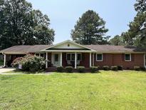 Charming brick ranch with a covered front porch, complemented by mature trees and a well-manicured lawn at 2433 Zacks Mill Rd, Angier, NC 27501