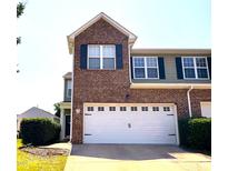 Two-story townhouse with brick facade, a two-car garage, dark shutters, and manicured landscaping at 2452 Bay Harbor Dr, Raleigh, NC 27604