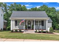Charming home featuring a welcoming front porch, American flag, and beautifully landscaped lawn at 267 Ashley Woods Ct, Clayton, NC 27527