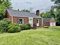 Charming brick home featuring a manicured lawn, shutters, and a detached two-car garage at 405 Foster Ln, Burlington, NC 27215