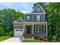 Charming two-story home featuring a welcoming front porch, gray siding, and an attached garage at 415 1St St, Apex, NC 27502