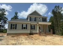 Two-story home featuring gray siding, black shutters, and a charming front porch with brick accents, and beautiful, ample windows at 80 Copper Penny Rd, Zebulon, NC 27597