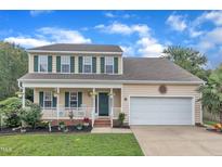 Charming two-story home with green shutters, a covered front porch, and a well-manicured lawn at 102 Lake Meadow Dr, Apex, NC 27502