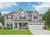 Charming two-story home featuring a well-manicured lawn, two-car garage, and inviting front porch with rocking chairs at 195 Solomon Dr, Cameron, NC 28326