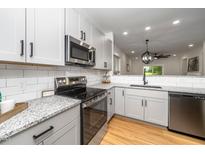 Modern kitchen with white cabinets, stainless steel appliances, granite counters and a subway tile backsplash at 2001 Turtle Point Dr, Raleigh, NC 27604