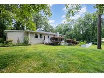 A spacious backyard featuring lush green grass and mature trees creates a private outdoor oasis at 3012 Optimist Farm Rd, Apex, NC 27539