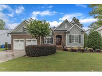 Charming home featuring a manicured lawn, lush landscaping, and a two-car garage at 3111 Virginia Pine Ln, Apex, NC 27539