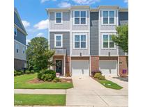 Charming townhome with gray siding, brick accents, well-kept lawn, and two-car garage in a desirable neighborhood at 336 Skymont Dr, Holly Springs, NC 27540