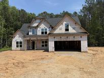 New two-story home under construction featuring an attached two-car garage and a covered porch in wooded area at 393 Abingdon Farms Dr, Selma, NC 27576