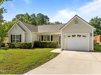 Charming single-story home featuring a well-manicured lawn, attached garage, and inviting front entrance at 608 Kinship Ln, Apex, NC 27502