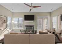 Inviting living room featuring a fireplace, ceiling fan, and sliding glass doors to the outdoor space at 6131 Summerpointe Pl # 101, Raleigh, NC 27606