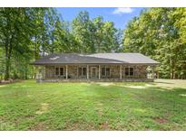 Charming stone home featuring a metal roof, expansive front yard, and inviting covered porch perfect for relaxing outdoors at 7849 Circle L Trl, Rougemont, NC 27572