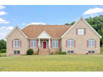 Charming brick home with red accents, landscaped lawn and inviting covered front entry at 8415 Meadow View Ln, Bahama, NC 27503
