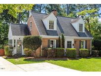 Charming brick home featuring dormer windows, complemented by well-maintained landscaping and a welcoming front yard at 1100 Brooks Ave, Raleigh, NC 27607
