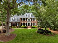 Charming brick home boasts lush lawn, manicured landscaping, and black shutters at 116 Berry Hill Dr, Raleigh, NC 27615