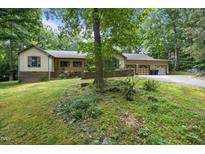 Charming home exterior featuring a lush lawn, mature trees, and a welcoming two-car garage at 2382 Council Rd, Graham, NC 27253