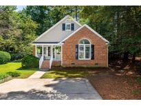 Charming brick and siding home featuring a welcoming front porch with white railing and a well-manicured lawn at 3616 Culater Ct, Raleigh, NC 27616