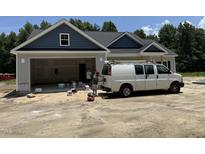 New construction home featuring a gray facade, open garage, and a work van in the driveway at 4024 N Nc 581 Hwy, Kenly, NC 27542