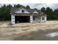 A new home under construction featuring an open two-car garage and a covered front porch at 4024 N Nc 581 Hwy, Kenly, NC 27542
