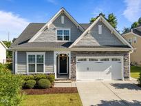 Charming home showcasing a stone and gray shake facade, complemented by a well-manicured lawn and a two-car garage at 427 Cedar Pond Ct, Knightdale, NC 27545