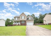 Charming two-story home with a well-manicured lawn and inviting front porch on a sunny day at 642 Pinevalley Ln, Sanford, NC 27332