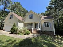 Inviting home featuring a manicured lawn, flowering bushes and a charming front porch at 65 Shorrey Pl, Youngsville, NC 27596