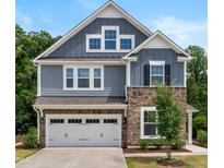 Beautiful two-story home featuring stone accents, a two-car garage, and professionally landscaped front yard at 7117 Crested Iris Pl, Durham, NC 27703