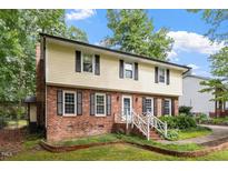 Charming two-story home featuring a brick facade, light yellow siding, black shutters and a well-manicured lawn at 7209 St Ledger Dr, Raleigh, NC 27613