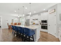 Bright kitchen features a large center island with blue bar stools, stainless appliances, and plenty of cabinet space at 9120 Dupree Meadow Dr, Angier, NC 27501