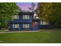 Charming two-story home featuring a manicured lawn, brick facade, and a welcoming orange front door at 939 Clarion Dr, Durham, NC 27705