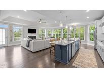 Open-concept living room flows into kitchen, boasting hardwood floors, fireplace, and abundant natural light at 10310 Sablewood Dr # 211, Raleigh, NC 27617
