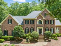 Elegant brick home featuring a symmetrical design, well-manicured landscaping, and classic architectural details at 1317 Woodgate Manor Ct, Raleigh, NC 27614