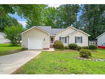 Charming single-story home with a well-maintained lawn, lush landscaping, and an attached garage at 1409 Beckworth Ct, Garner, NC 27529