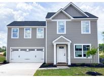 Charming two-story home featuring a white garage door, inviting entrance, and landscaped front yard at 302 Rosewood Dr, Sanford, NC 27330