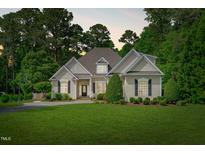 Charming single-story home featuring a lush green lawn, mature trees, and a welcoming front entrance at 3104 Whitehart Ln, Apex, NC 27539