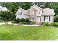 Charming two-story home with a stone facade and beautifully landscaped front yard, perfect for a growing Gathering at 4305 Heathgate Ln, Raleigh, NC 27613