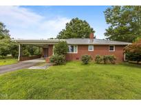 Charming brick ranch home with a metal roof, carport, and a well-maintained front yard at 5918 Efland Cedar Grove Rd, Cedar Grove, NC 27231