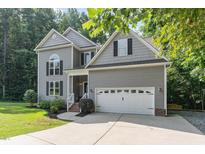 Charming gray two-story home with a two-car garage, landscaped yard, and inviting curb appeal at 6717 Country Hollows Ln, Holly Springs, NC 27540