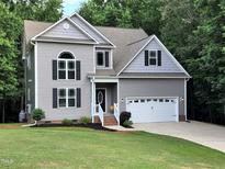 Charming two-story home with a manicured lawn, attached two car garage and classic gray siding at 6717 Country Hollows Ln, Holly Springs, NC 27540