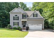 Charming gray two-story home with attached two-car garage and well-maintained landscaping at 6717 Country Hollows Ln, Holly Springs, NC 27540