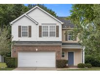 Charming two-story home with a brick and siding exterior, complemented by a well-maintained lawn and mature trees at 702 Calavaras Ln, Knightdale, NC 27545