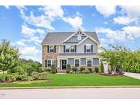 Charming two-story home featuring a beautifully landscaped front yard and a combination of stone and siding accents at 710 Legacy Falls S Dr, Chapel Hill, NC 27517